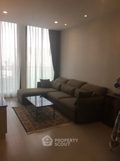Modern living room with large sofa and floor-to-ceiling windows in a stylish apartment.