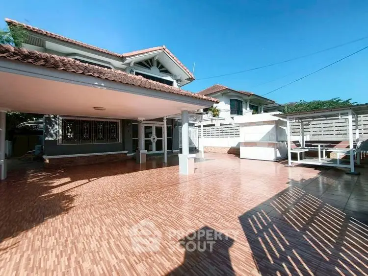 Spacious outdoor patio of a modern house with tiled flooring and seating area.