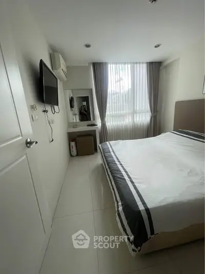 Modern bedroom with natural light, featuring a sleek design and cozy atmosphere.