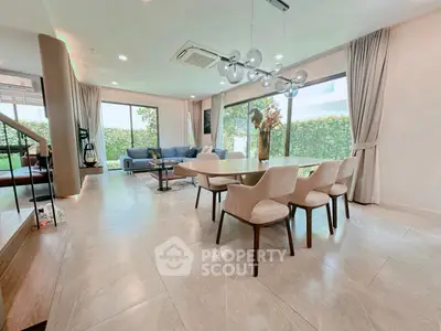 Spacious modern living room with elegant dining area and large windows offering garden views.