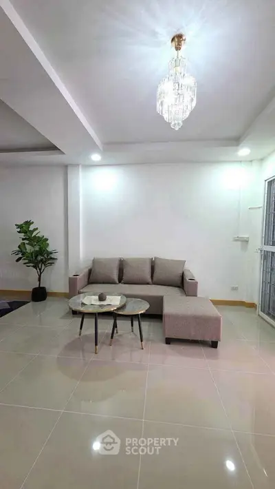 Spacious living room with elegant chandelier and modern furniture in a stylish apartment.
