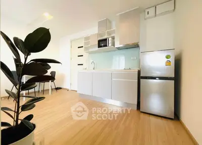 Modern kitchen with sleek design, featuring stainless steel fridge and microwave, in a bright open space.