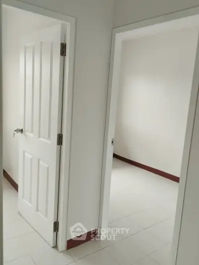 Minimalist interior with white doors and tiled flooring in a residential property.