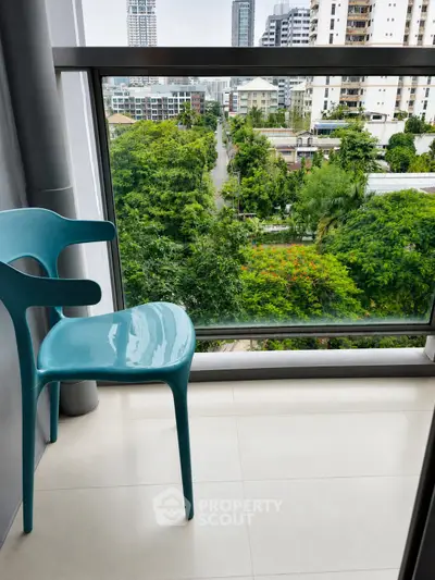 Modern balcony with city view and stylish blue chair, perfect for urban living.