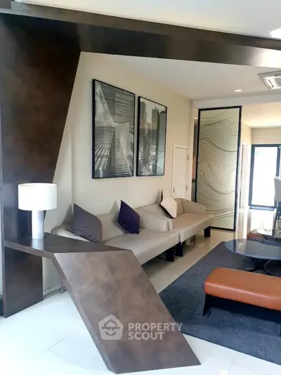 Modern living room with stylish decor and unique architectural elements, featuring a cozy seating area and contemporary artwork.