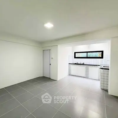Spacious open-plan kitchen with modern tiled flooring and ample natural light.