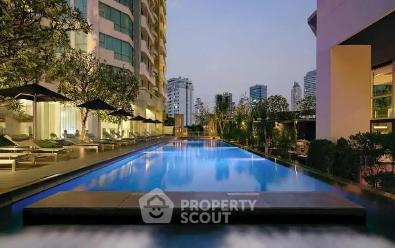 Luxurious urban apartment complex with stunning pool and city skyline view.