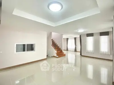 Spacious modern living room with elegant staircase and large windows