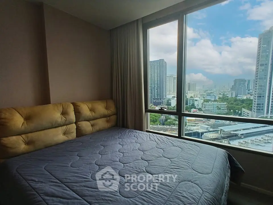 Spacious bedroom with stunning city view from large windows in modern high-rise apartment.