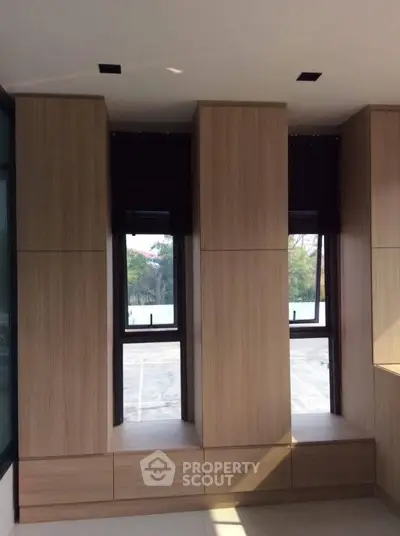 Modern interior with sleek wooden cabinetry and large windows offering natural light.