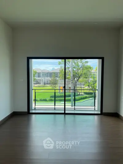 Spacious room with large window offering a serene garden view, perfect for modern living.