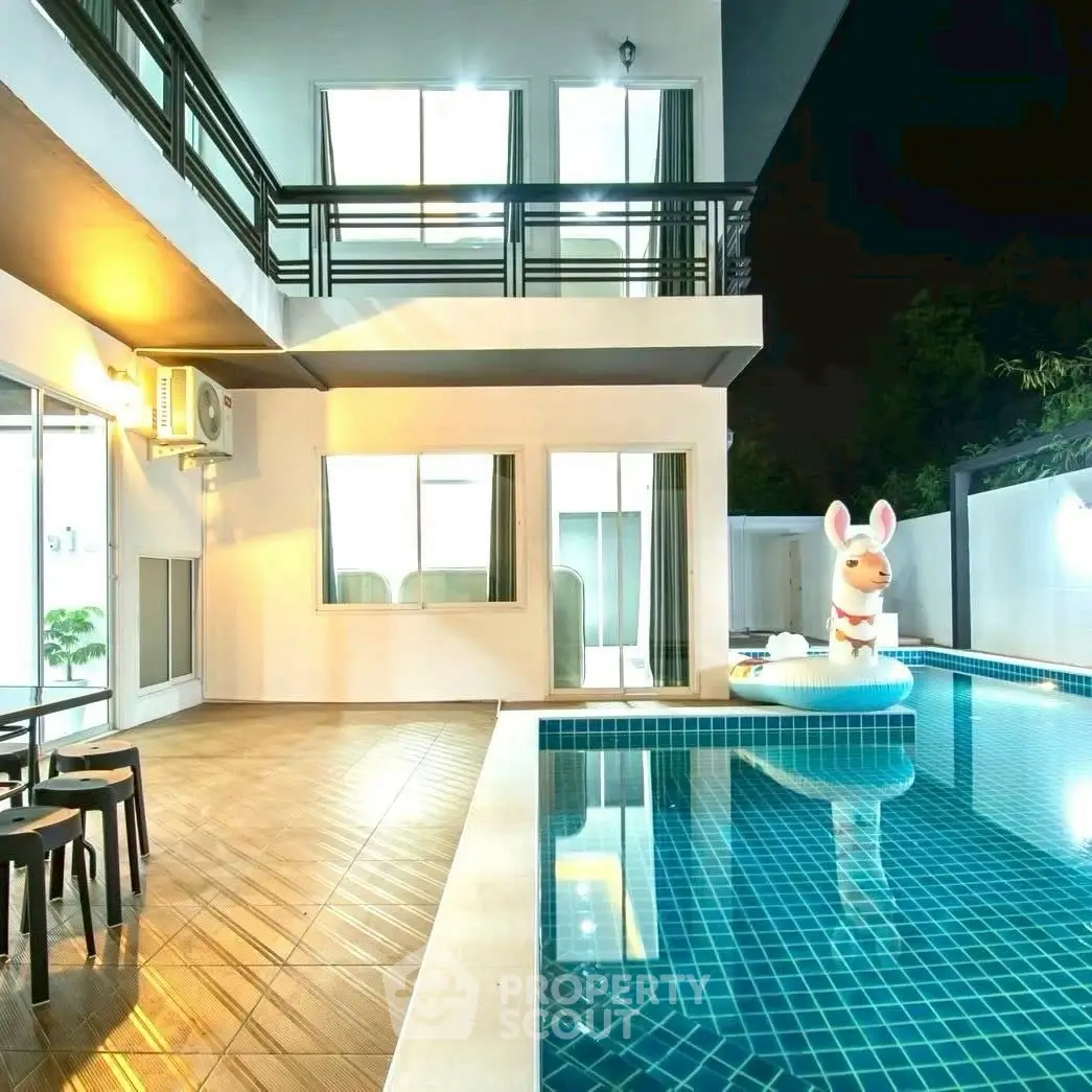 Luxurious modern home with private pool and stylish outdoor seating area at night.