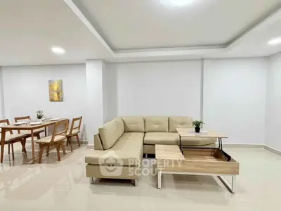 Spacious modern living room with elegant beige sofa and stylish dining area, perfect for entertaining.