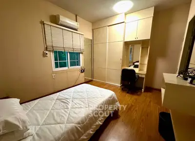 Cozy bedroom with wooden flooring, built-in wardrobe, and study desk, perfect for a comfortable living space.