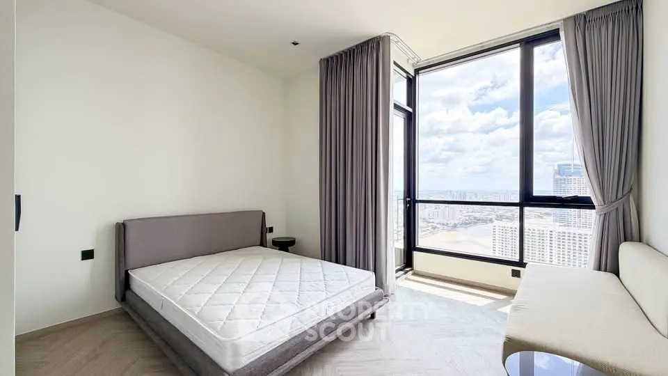 Modern bedroom with large window offering stunning city view, featuring minimalist decor and natural light.