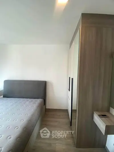 Modern bedroom with sleek design and wooden flooring, featuring a stylish bed and wardrobe.