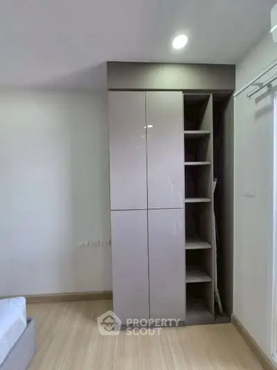 Modern bedroom with sleek built-in wardrobe and wooden flooring, showcasing minimalist design.