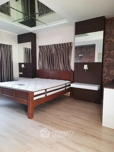 Spacious bedroom with elegant wooden bed and modern decor, featuring large windows and stylish curtains.