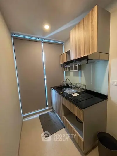 Modern compact kitchen with sleek cabinetry and black countertop in a cozy apartment.