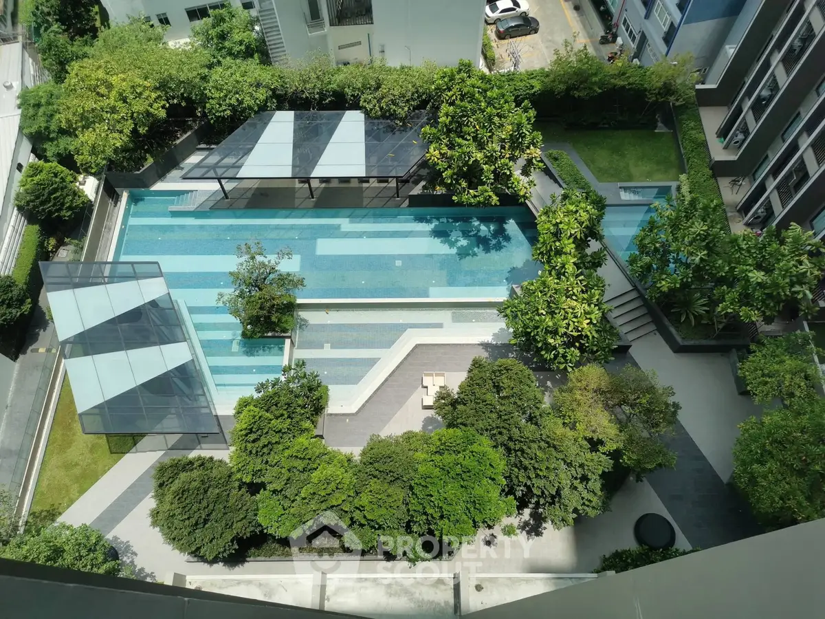 Stunning aerial view of modern apartment complex with lush greenery and inviting swimming pool.