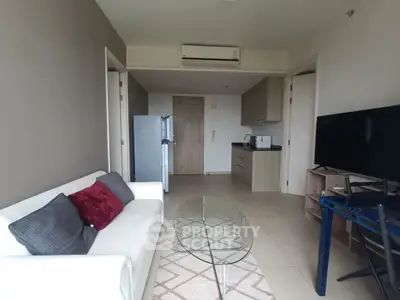 Modern living room with sleek furniture and open kitchen layout, featuring a cozy sofa and flat-screen TV.