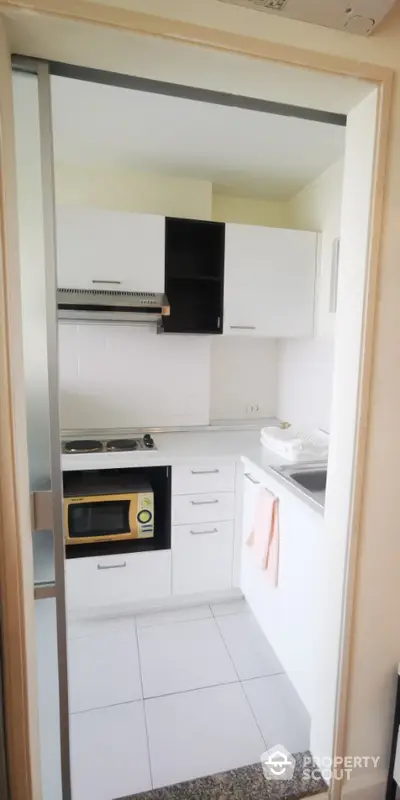 Modern compact kitchen with sleek white cabinets and built-in appliances