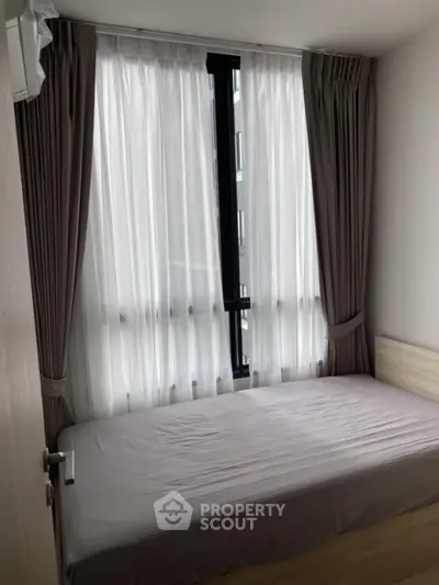 Cozy bedroom with large window and elegant curtains in modern apartment.