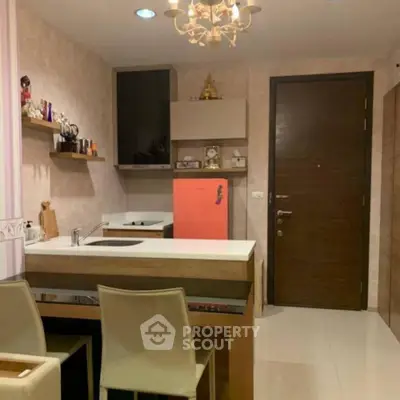 Modern kitchen with stylish decor and compact layout, featuring a vibrant red fridge and elegant lighting.