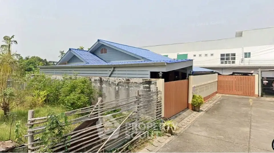 Charming single-story home with blue roof and spacious driveway in a serene neighborhood.
