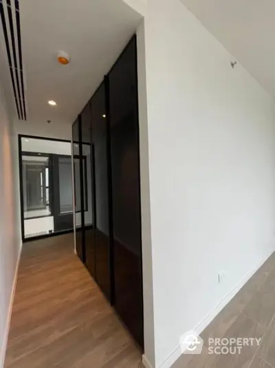 Modern hallway with sleek black glass doors and wood flooring