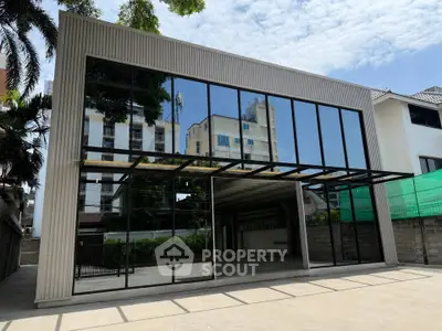Modern commercial building with large glass facade and spacious parking area, ideal for business opportunities.