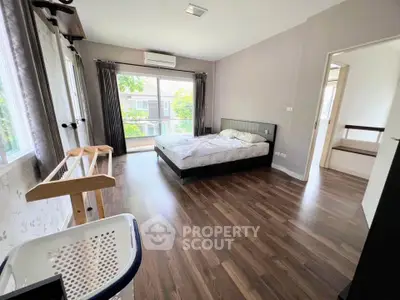Spacious bedroom with large windows and wooden flooring in modern home