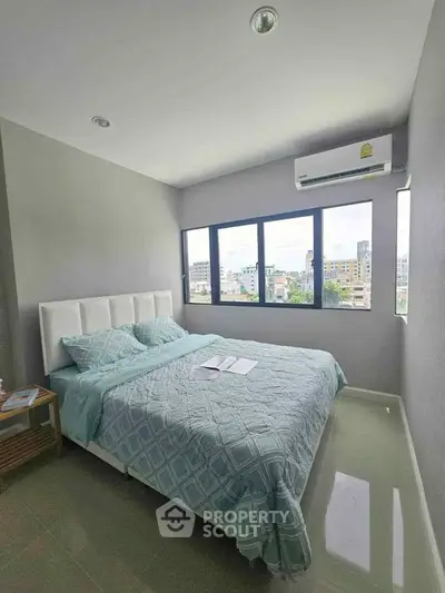 Modern bedroom with large windows and city view, featuring a comfortable bed and air conditioning.