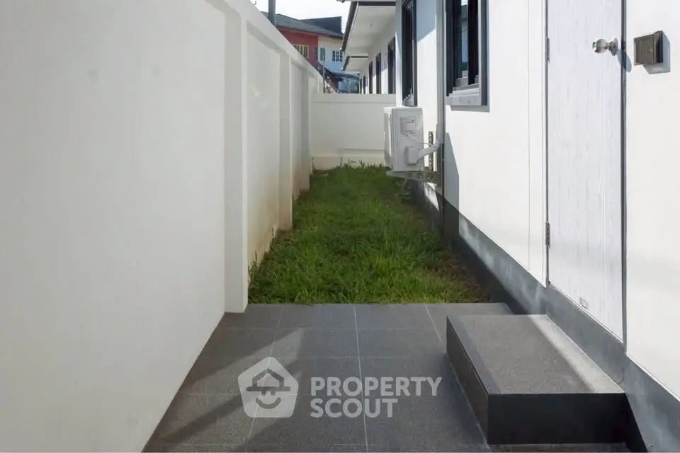 Modern side yard with grass and white walls in a contemporary home