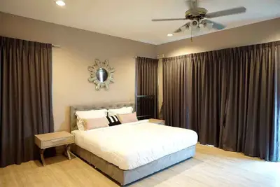 Spacious bedroom with elegant decor and ceiling fan, featuring large windows with dark curtains.