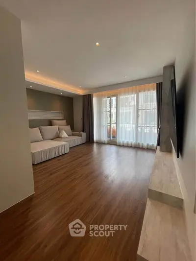 Spacious modern living room with elegant wood flooring and large windows