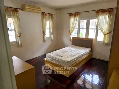 Spacious bedroom with natural light and wooden flooring