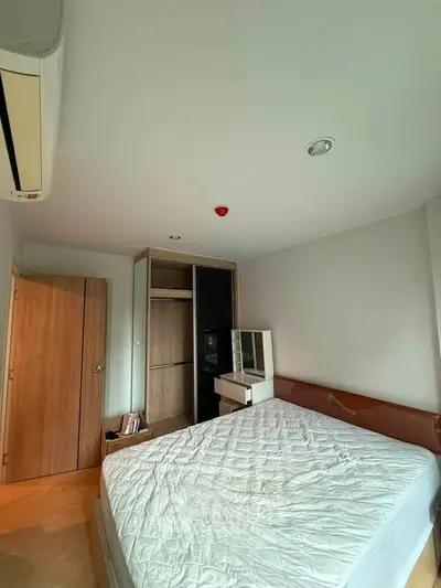 Cozy bedroom with wooden flooring, air conditioning, and ample closet space in modern apartment.