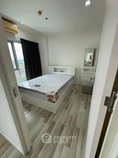 Modern bedroom with large window and sleek flooring in high-rise apartment.