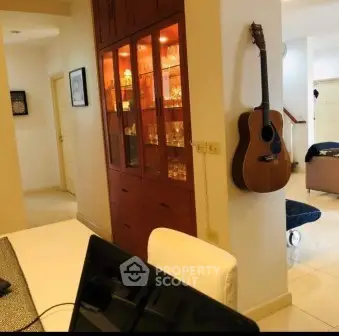 Charming living room with built-in cabinet and wall-mounted guitar, perfect for music lovers.