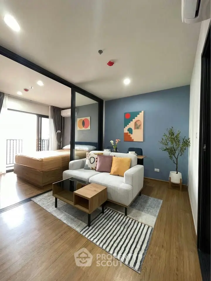 Modern living room with stylish decor and open layout leading to a cozy bedroom.