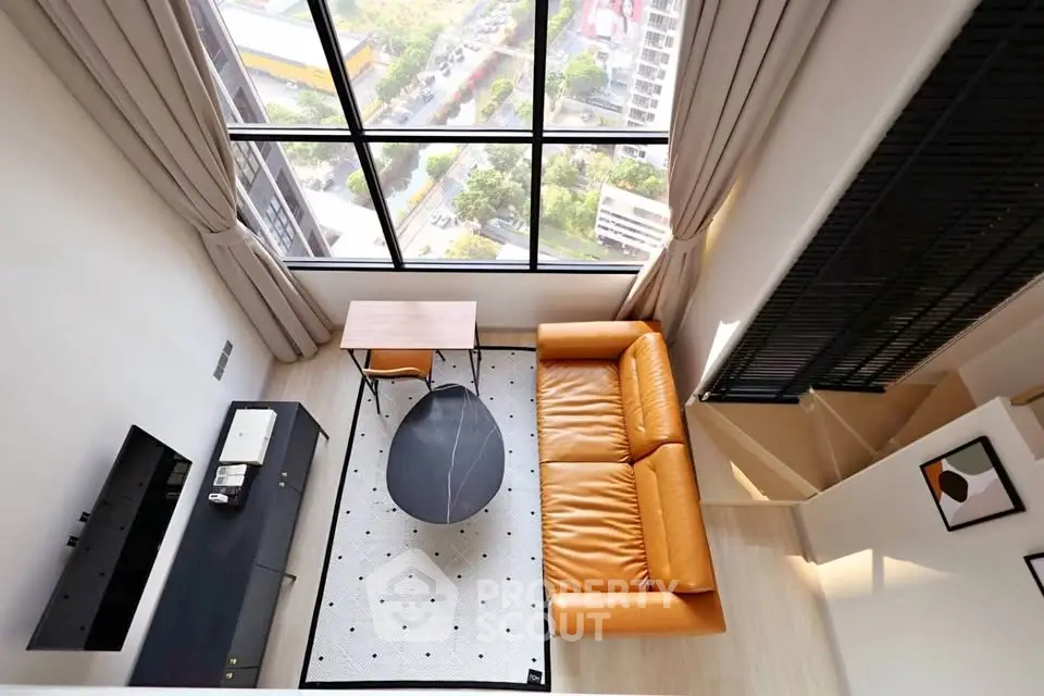 Stunning loft living room with high ceilings and large windows offering a breathtaking city view.