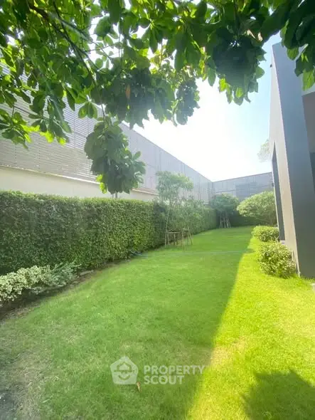 Lush green garden area with manicured hedges and modern building exterior, perfect for relaxation.