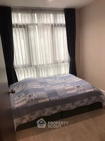 Cozy bedroom with large window and elegant curtains, perfect for relaxation.