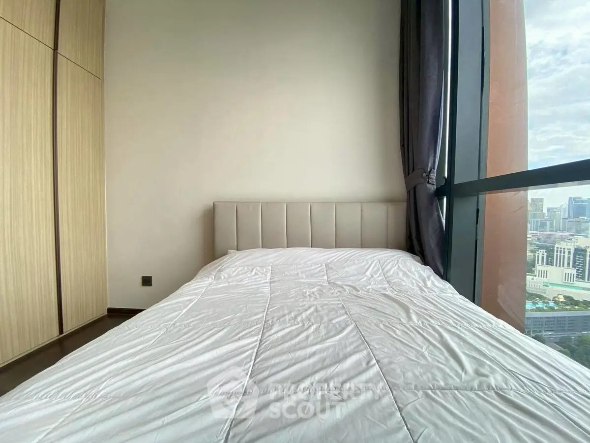 Modern bedroom with large window offering stunning city views and ample natural light.