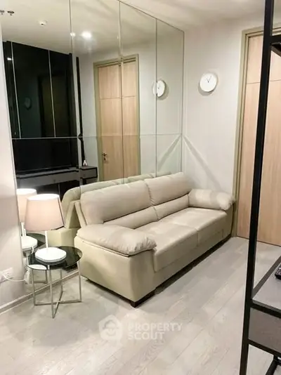 Modern living room with beige sofa and mirrored wall for spacious feel.