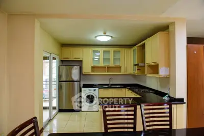 Modern kitchen with stainless steel appliances and washing machine in open layout design.