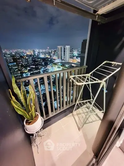Stunning city view from a high-rise balcony with plant and drying rack.