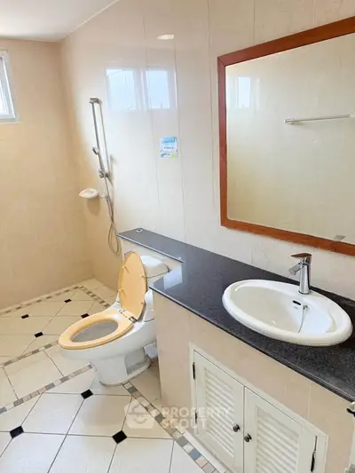 Spacious bathroom with modern fixtures and elegant tile design, featuring a large mirror and ample counter space.