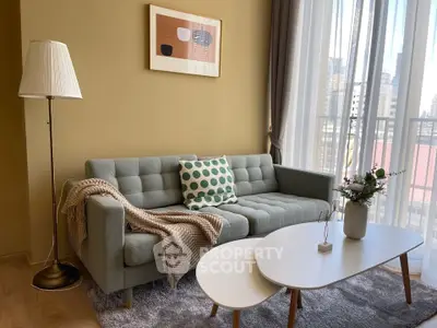 Chic living room with modern sofa, stylish decor, and large windows offering city views.